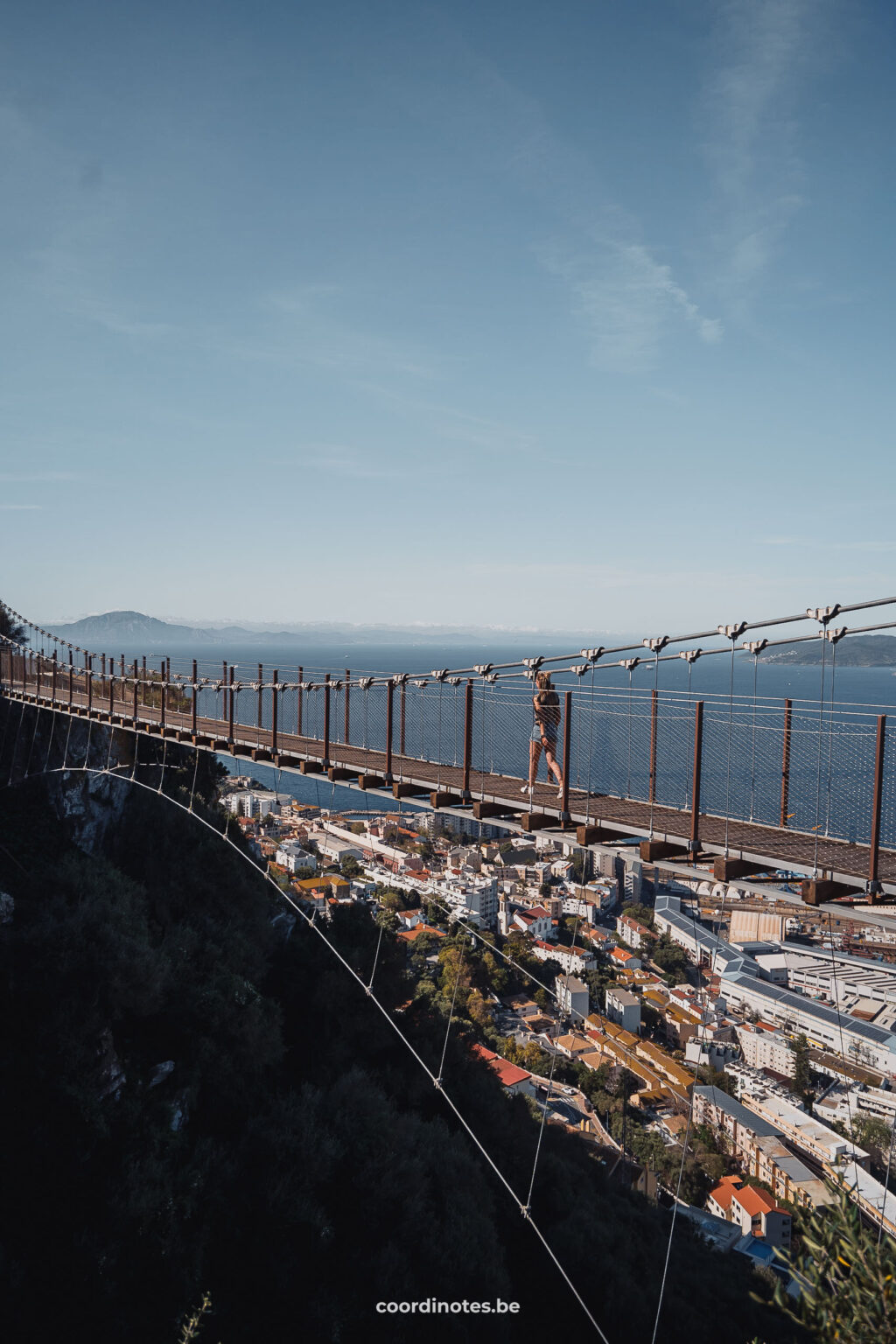 Sarah walking over the windsor Suspension bridge with the view on Gibraltar and the sea in the background