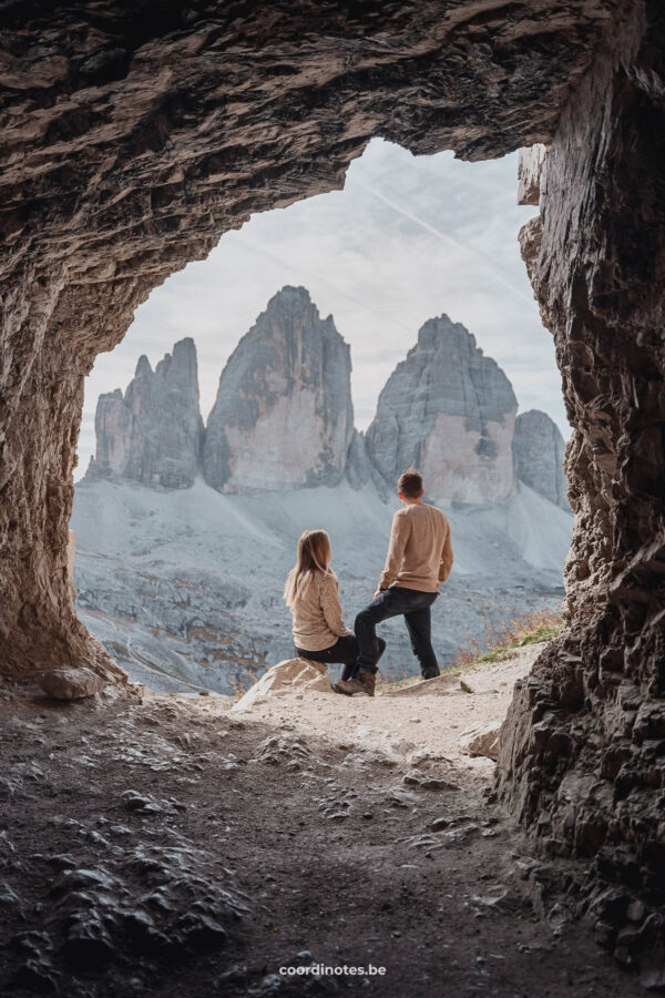 View from inside a cave with us in front and the three peaks of Tre Cime di Lavaredo in the background