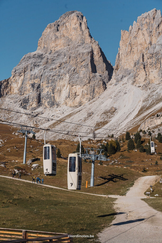 Tiny cable cars at Forcella del Sassolungo looking like coffins in front of two mountain peaks