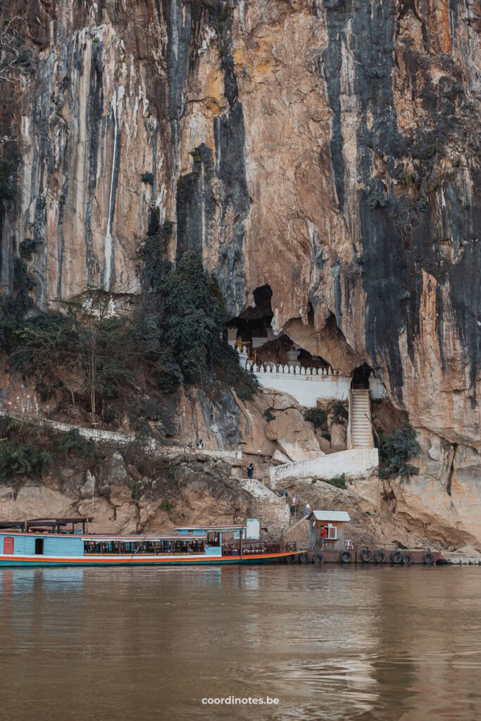 The view on the Phak Ou Caves and the stairs to the entrance, with a boat in front, seen from the slow boat on the Mekong river