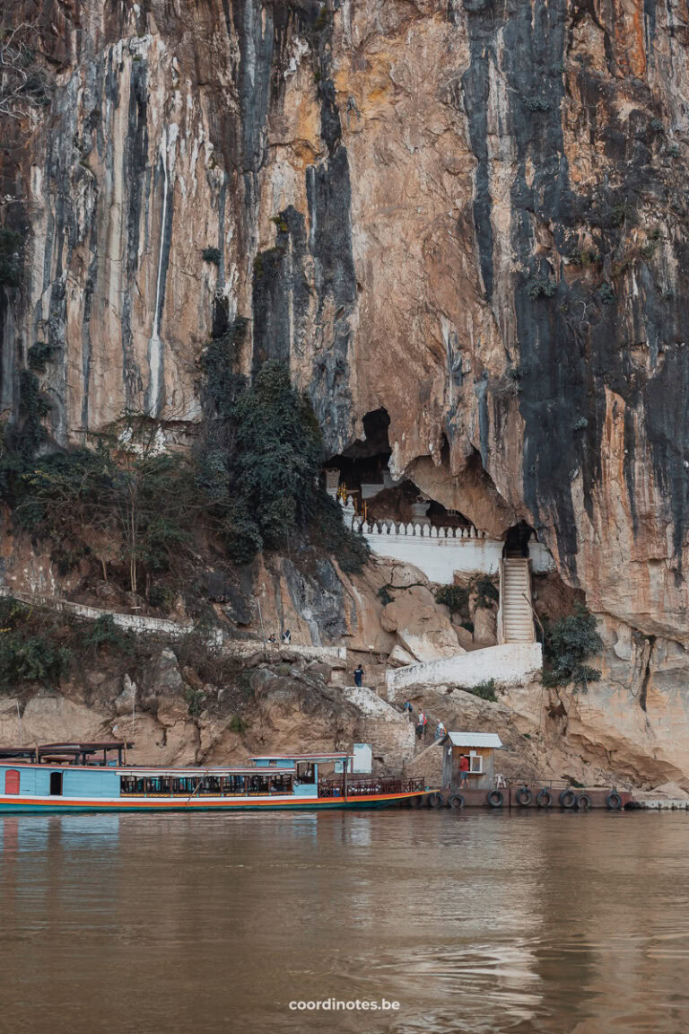 The view on the Pak Ou Caves and the stairs to the entrance, with a boat in front, seen from the slow boat on the Mekong river.