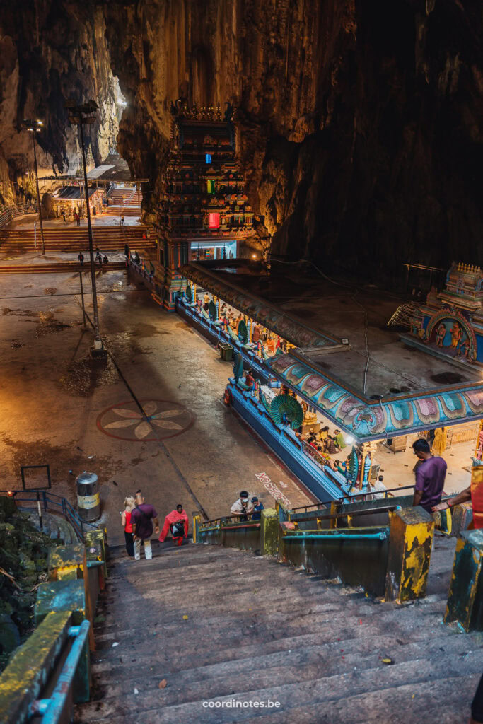 A stairs to a square with a colorful temple inside the Batu Caves.