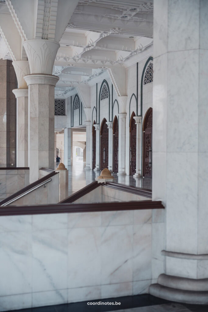 The inside of the Wilayah Persekutuan Mosque with marble columns, arches and walls.