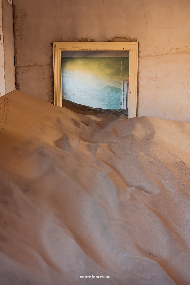 a doorway in a wall, half blocked because the rooms are filled with sand.