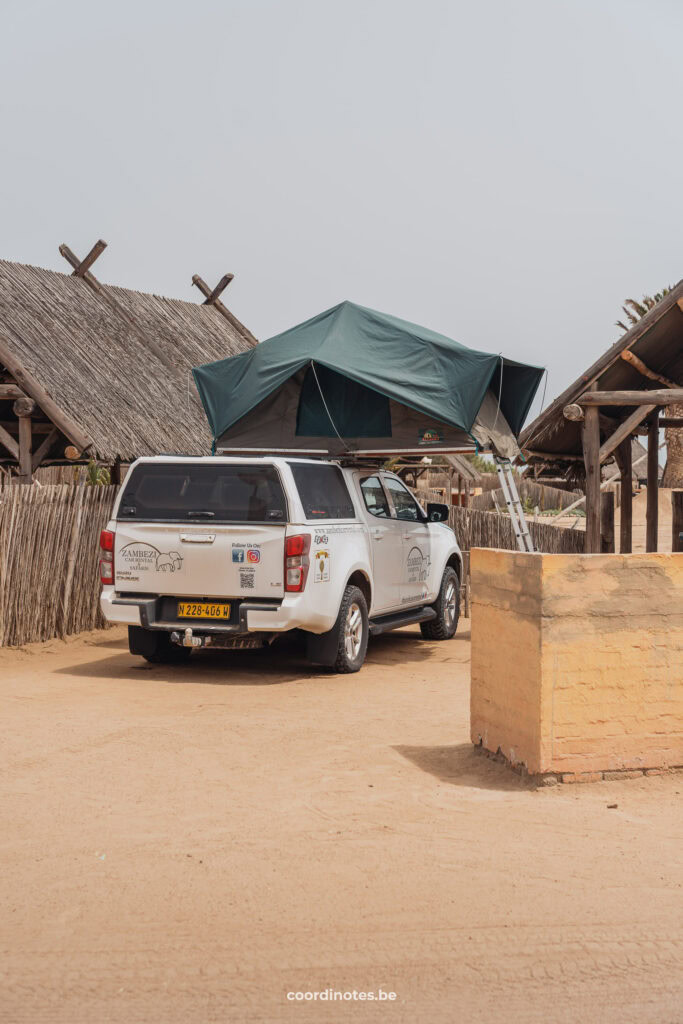 Our pick-up truck with open rooftop tent between huts with thatched roofs at Tiger reef campsite