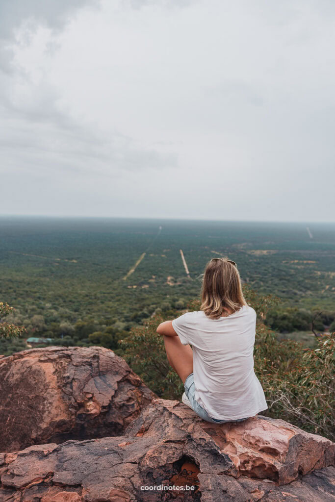 Sarah sitting on a rock on top of a mountain watching over a huge plane filled with trees.