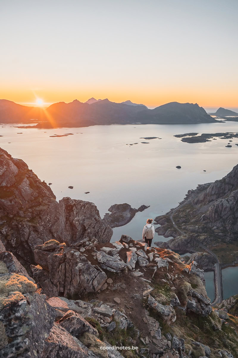 Sarah on top of Festvågtind watching over the fjord, the mountains and the sunset in the background