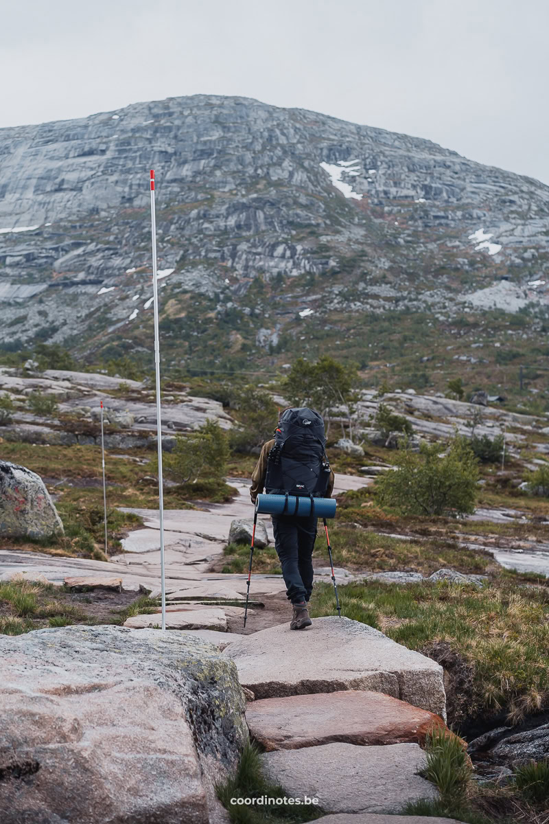 Cédric hiking with a backpack on a rocky trail with a mountain in the background on the way to Trolltunga