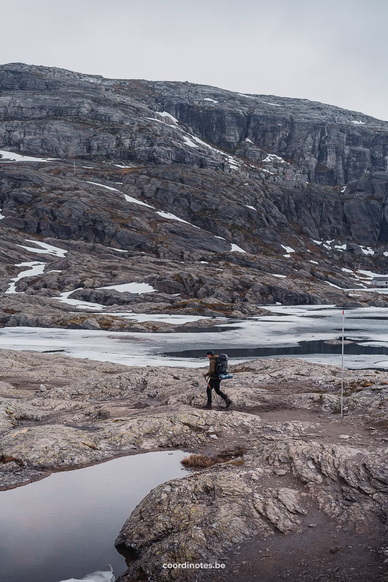 Cédric hiking over the rocks with still some patches of snow on the mountains on the way to Trolltunga