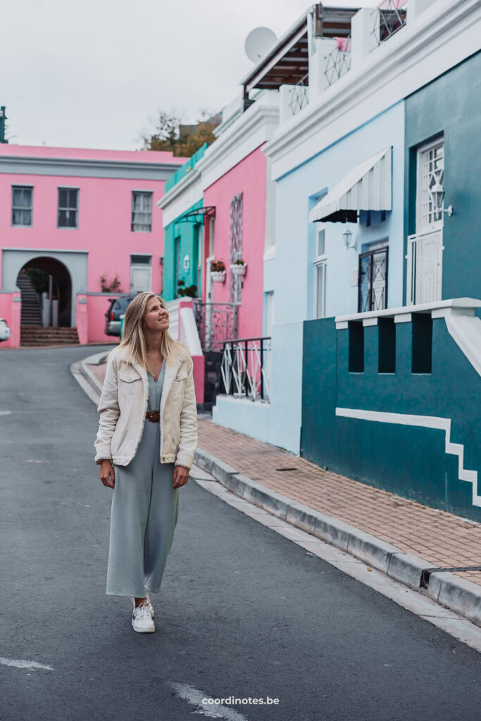 Sarah die langs de blauw en roos gekleurde huisjes wandelt in Bo-Kaap in Kaapstad