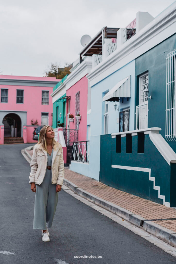 Sarah die langs de blauw en roos gekleurde huisjes wandelt in Bo-Kaap in Kaapstad