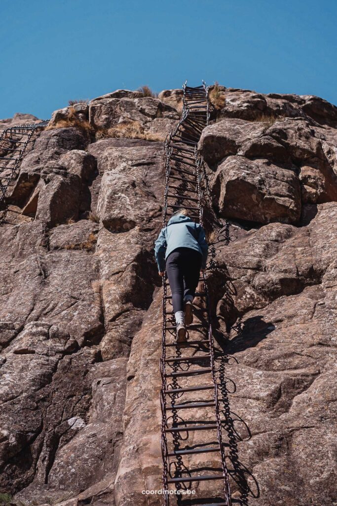 Sarah die op een 40m hoge ketting ladder klimt naar de top van een rots