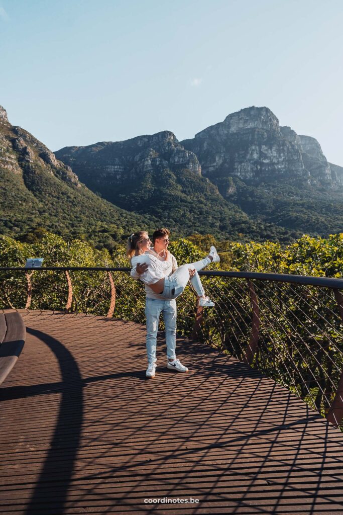 Cédric die Sarah optilt op het boomtop wandelpad in Kirstenbosch Botanical Garden met een berg op de achtergrond