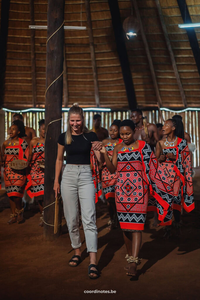 Sarah aan het dansen met vrouwen, gekleed in een traditioneel rood gewaad uit Eswatini