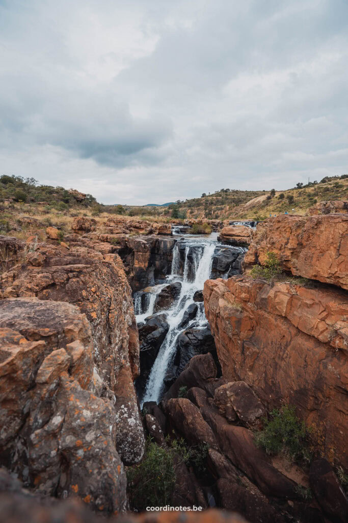 Een waterval in een oranje canyon bij Bourke's Luck Potholes