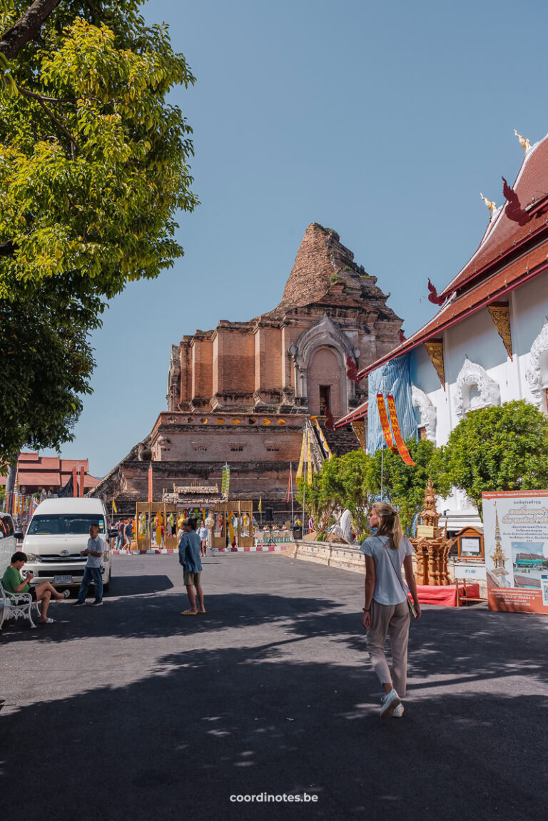 Sarah walking next to a white temple towards the ruin of the Wat Chedi Luang temple in Chiang Mai.