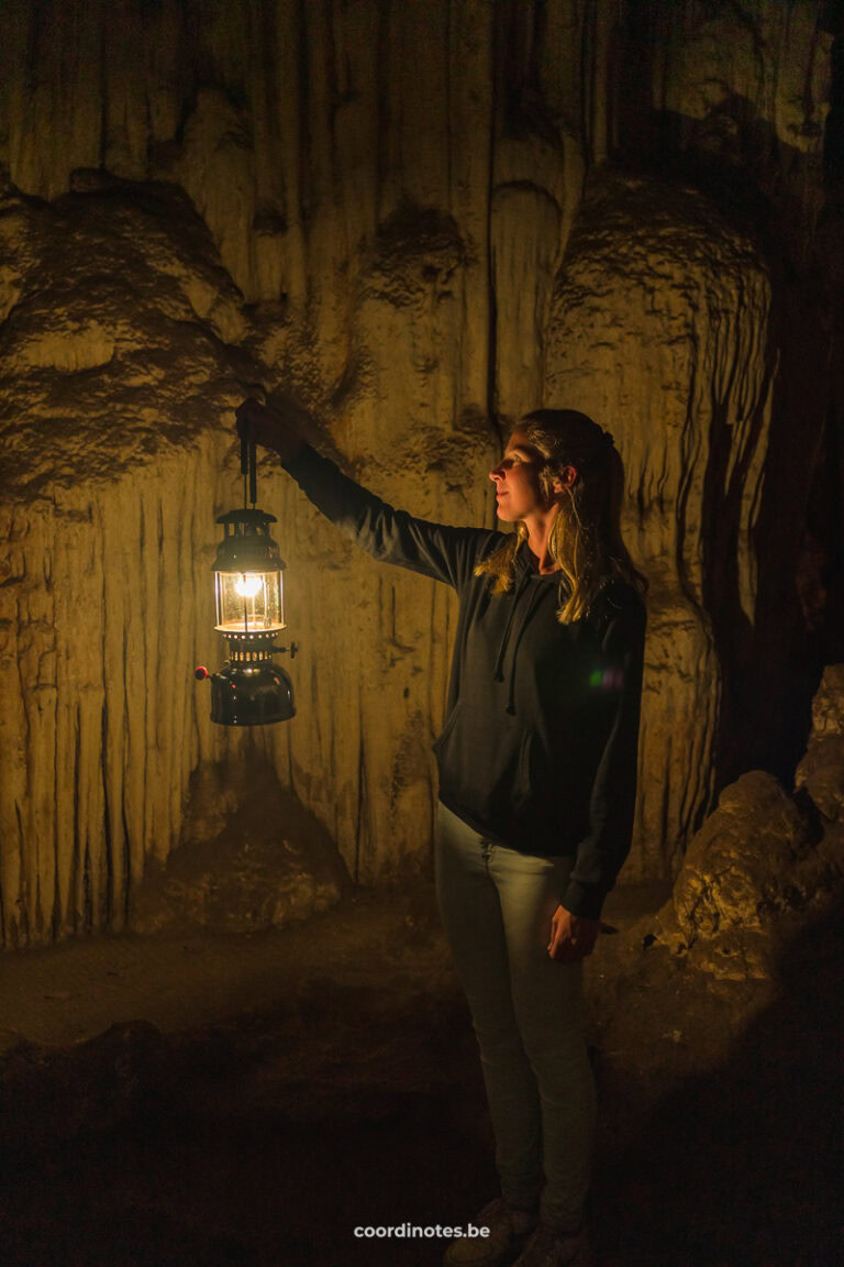 Sarah holding a gas lamp up inside the Tham Lod Cave, in front of the limestone stalagmites.