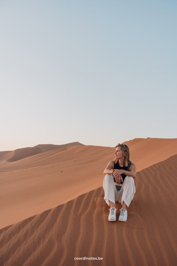 Sarah sitting on sand in Sossusvlei, Namibia