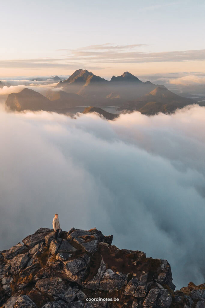 Sarah op de top van de Stornappstinden berg in Noorwegen in de wolken, met nog meer bergtoppen op de achtergrond