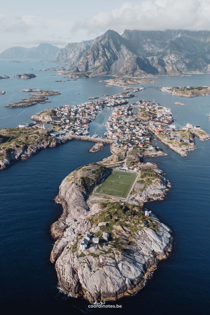 Een voetbalveld op een schier eiland met nog meer eilandjes en bergen op de achtergrond in Henningsvaer in Lofoten.