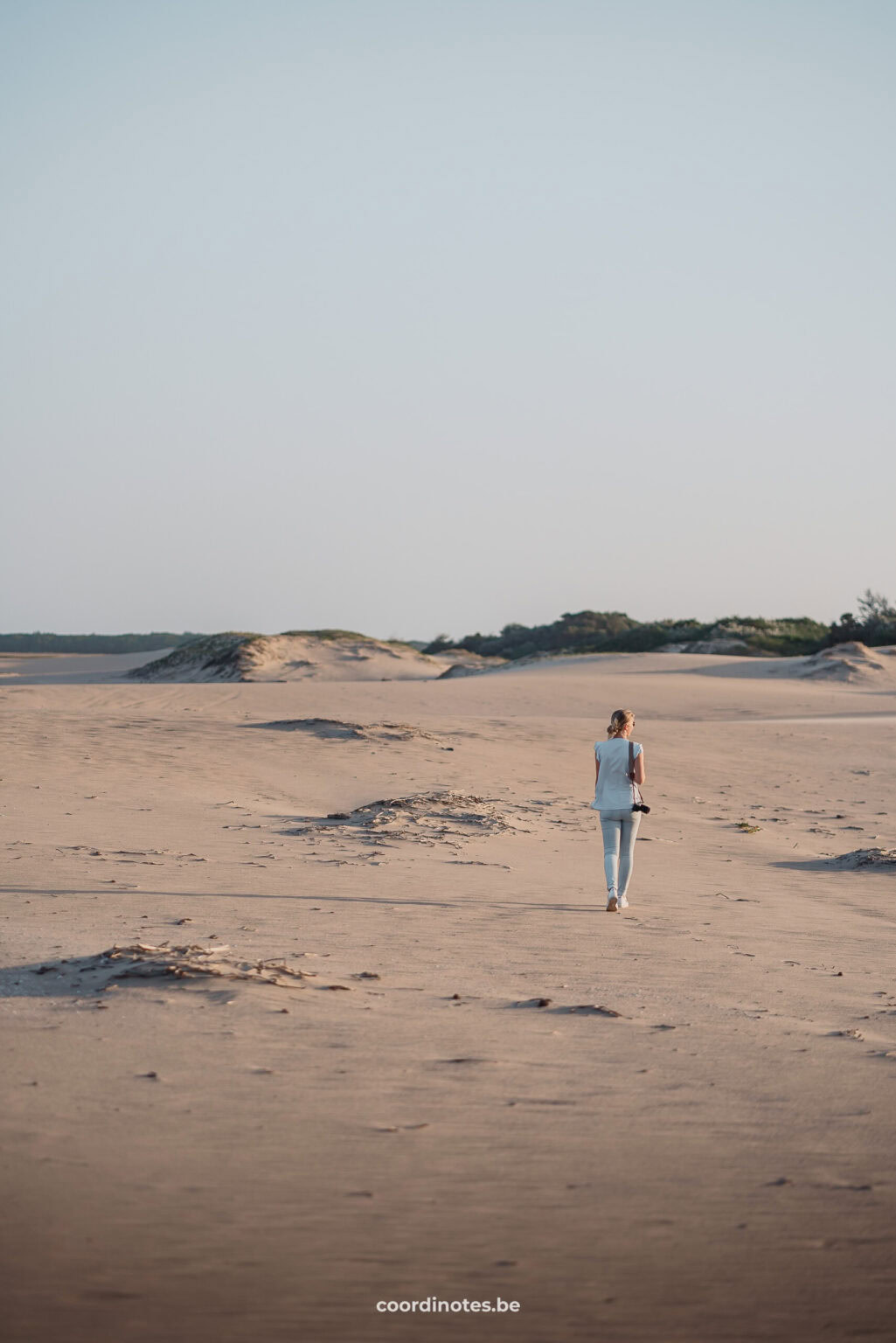 Sarah die door de duinen wandelt van het strand in St Lucia